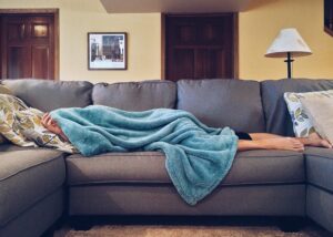 person laying on couch with blanket