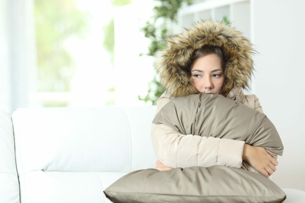 Woman warmly clothed in a cold home | colorado springs hvac service